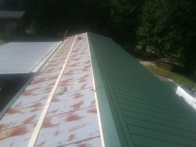 Old rusted panels beside newly installed green metal roofing — Wind Damage Roof Repair by Roofing Brothers in Lavinia