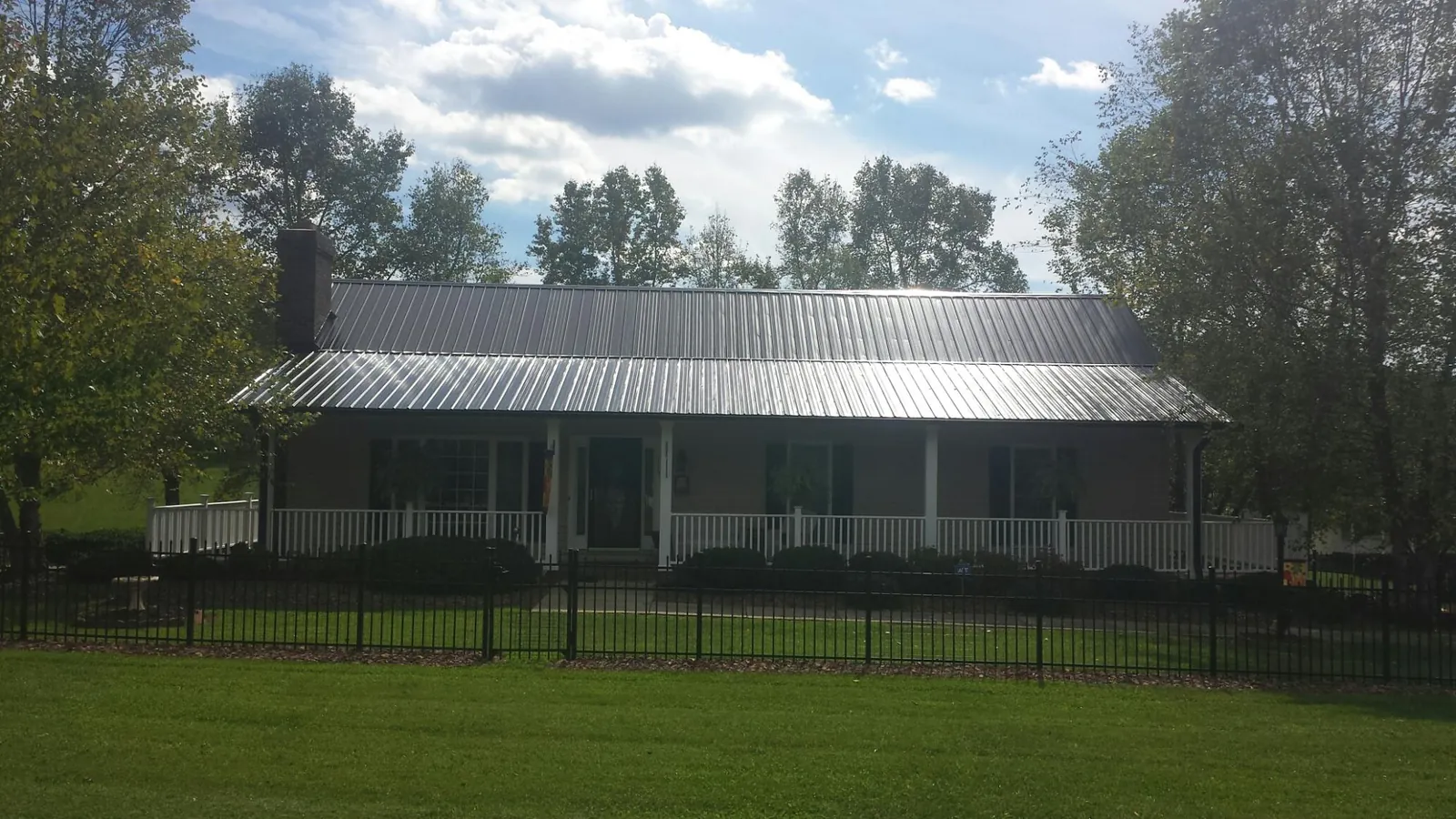 Gray metal roof on a brick ranch with a full width front porch — Gutter Guard Installation work by our crew in Lavinia