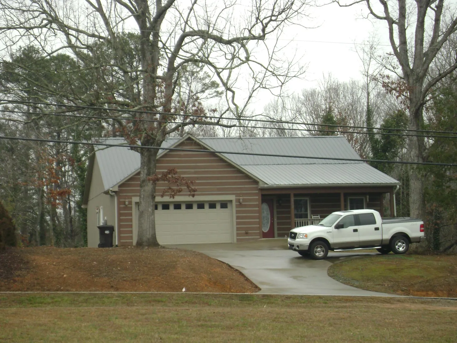 Gray metal roof on a log sided house with an attached two car garage in Lavinia